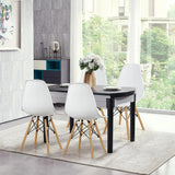 Dining area with a black table and white chairs in a modern room with large windows.