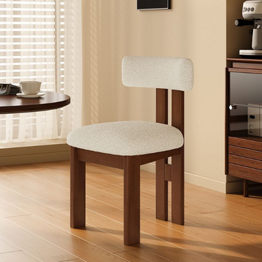 Wooden chair with white cushioned seat and backrest in a room with a window and desk.