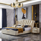 A luxury cream tufted leather bed with a low platform frame, styled in a modern bedroom with gray marble walls, gold accents, a gold-framed chandelier, and matching nightstands.