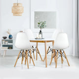 Dining room with a wooden table and white chairs, featuring a lamp and decor items.
