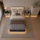Overhead view of a modern bedroom featuring a bed with a tufted gray mattress, white bedding, and warm ambient lighting from built-in LED panels on the headboard and beneath the bed, flanked by matching nightstands and a white dresser.